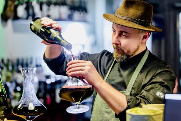 Ritualul vinului Chef Silviu decantează vin roșu într-o carafă de cristal, într-o scenă de rafinament culinar.