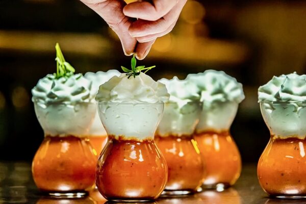 Armonia detaliului Chef Silviu adaugă o frunză verde peste un preparat stratificat cu spumă albă și bază roșie, surprins în momentul final al platingului.